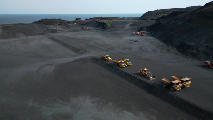 Aerial drone footage of a stone quarry where heavy machines stand aside