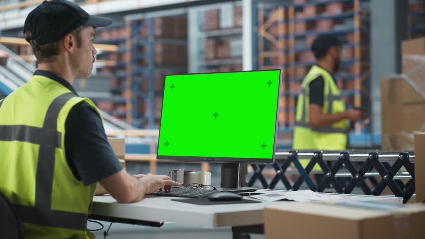 Caucasian Male Stocking Associate Using Green Screen Chromakey Desktop Computer In Distribution Facility. Multiethnic Male Warehouse Worker Scanning Barcodes On Cardboard Boxes WIth Online Orders. Royalty-Free Stock Footage #1107299437
