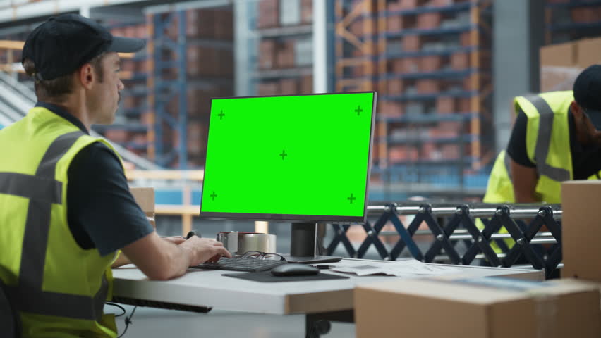 Caucasian Male Stocking Associate Using Green Screen Chromakey Desktop Computer In Distribution Facility. Multiethnic Male Warehouse Worker Loading Cardboard Boxes On Automated Conveyor Belt. Royalty-Free Stock Footage #1107299441