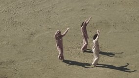three women in casual clothes are dancing. three women in the desert. top view of women.slow motion video. High quality Full HD video recording