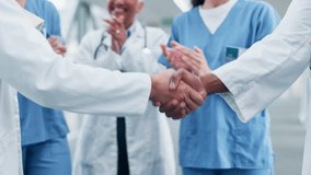 Doctor, handshake and people applause in teamwork, meeting or partnership together at the hospital. Closeup of medical or healthcare professional shaking hands and clapping in celebration or success - Powered by Shutterstock - Get 15% off with code: PIKWIZARD15