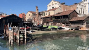 Last gondolas repairman Squero di San Trovaso Boatyard. Beautiful traditional ornate gondola boats navigating in the narrow canals of Venice, in Italy. Travel destination background in 4k resolution.