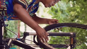 Vertical video Fit and dedicated multiracial pair inspecting damaged bicycle for maintenance using professional equipment. Boyfriend mending bike pedal and talking with girlfriend who is removing