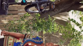 Vertical video Motivated black woman fine-tuning bicycle tire in home yard with an assortment of professional tools. Young african american lady realigning and securing bike wheel for summer leisure