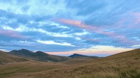 Panoramic time lapse of clouds above mountains and green hills at sunset. Time lapse video in Bucegi natural park, Romania.