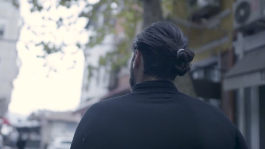 Back of man walking on the street in slow motion