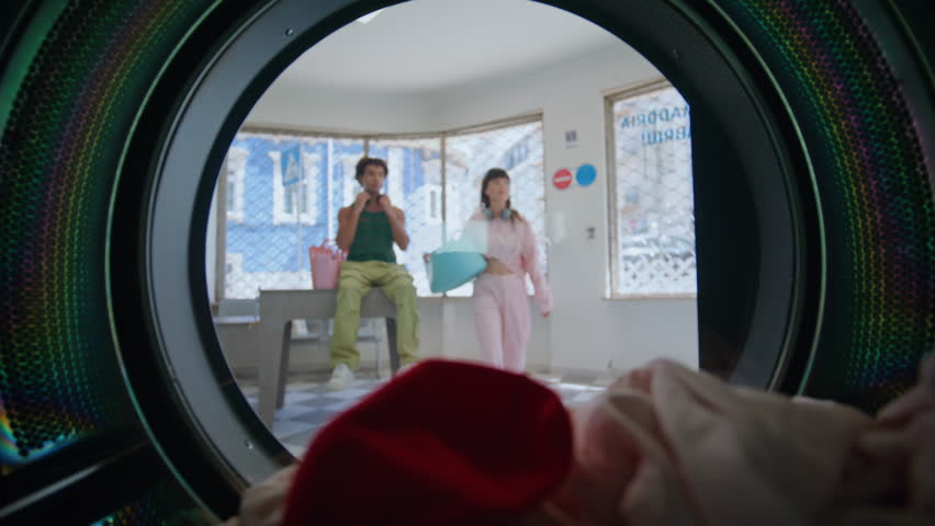 Casual girl taking laundry out machine closeup. Confused woman holding colored clothes with red sock laundering service. Urban teenager with headphones open drum feeling upset at public laundromat. Royalty-Free Stock Footage #1107327823