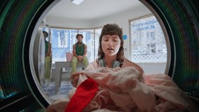 Casual girl taking laundry out machine closeup. Confused woman holding colored clothes with red sock laundering service. Urban teenager with headphones open drum feeling upset at public laundromat. - Powered by Shutterstock - Get 15% off with code: PIKWIZARD15