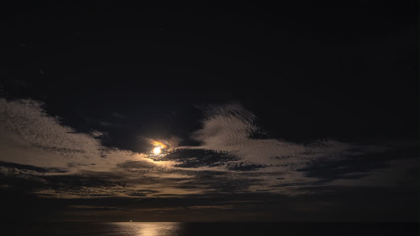 Time-lapse with moving clouds in the full moon night sky