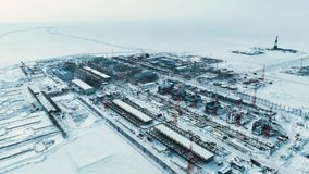 A big city is being built on an ice field. Time lapse. People and cars are moving. Construction works are underway. The North of Russia. A clear winter day.