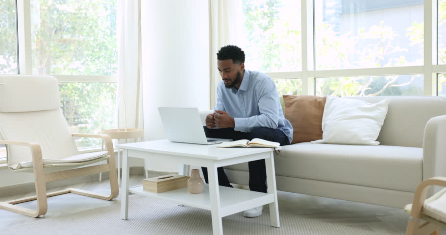 Millennial African business man sit on couch at home lead formal conversation through videocall. On-line counselling event, consultation to client remotely use videoconference application and computer Royalty-Free Stock Footage #1107333009