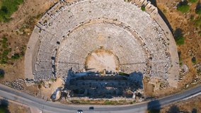 In this captivating aerial video, the remnants of the ancient city of Perge come into view, showcasing a stunning amphitheater nestled within the historic ruins. This amphitheater, a testament to the
