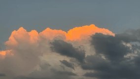 The upper part of the clouds is orange and the lower part is black. The orange evening sun dances above the clouds. sunset sky cloud red cloudscape time lapse background.