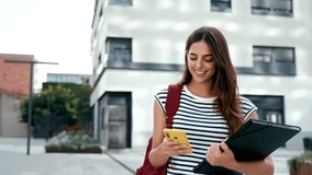 Young Hispanic Woman walking while using cell phone. Happy university student girl smiling in the city - Powered by Shutterstock - Get 15% off with code: PIKWIZARD15