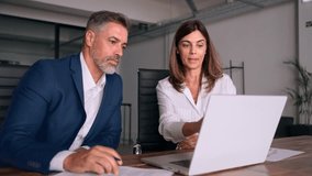 Mature 50s age Latin business man mentoring mid age European business woman discussing project on laptop in office. Two colleagues, group of partners, professional business people working together. - Powered by Shutterstock - Get 15% off with code: PIKWIZARD15