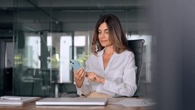 Smiling Latin Hispanic mature adult professional business woman using mobile phone cellphone. European businesswoman CEO holding smartphone using fintech application standing at workplace in office. - Powered by Shutterstock - Get 15% off with code: PIKWIZARD15