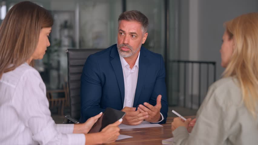 Group of diverse partners mature Latin business man and European business women discussing project with documents at table in office. Team of colleagues professionals business people working together. - Powered by Shutterstock - Get 15% off with code: PIKWIZARD15