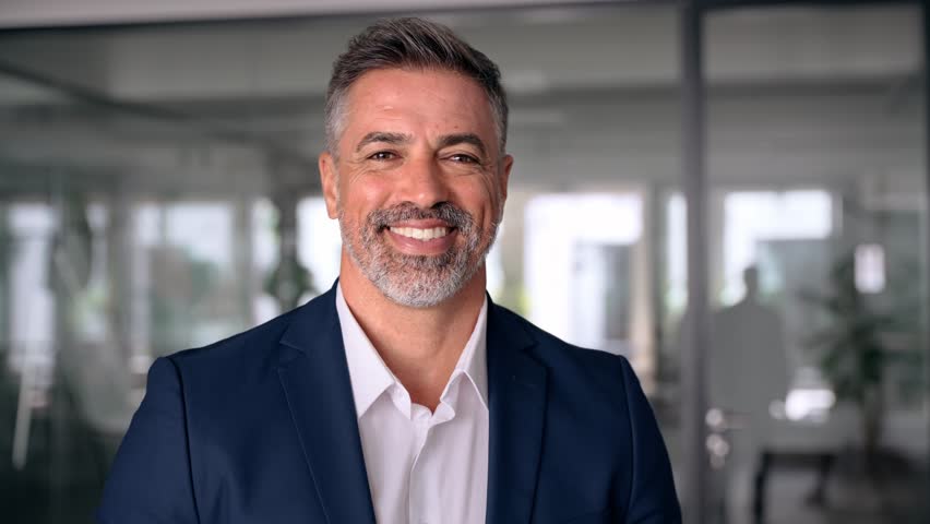 Headshot close up portrait of indian or latin confident mature good looking middle age leader, ceo male businessman in suit on office background. Handsome hispanic senior business man smile at camera. | Shutterstock HD Video #1107342085
