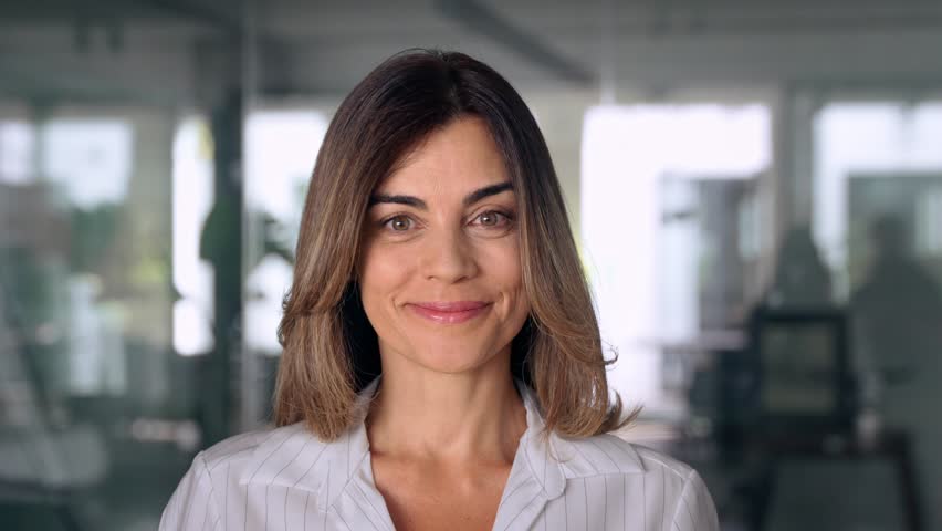 Headshot close up portrait of latin hispanic confident mature good looking middle age leader, ceo female businesswoman on blur office background. Gorgeous beautiful business woman smiling at camera. Royalty-Free Stock Footage #1107342093