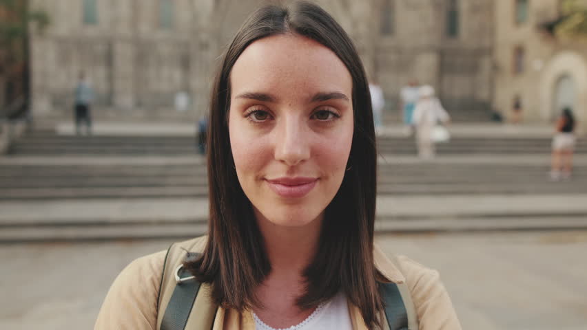 Close up, traveler girl looking at the camera at the old building in the historical part of the old European city background