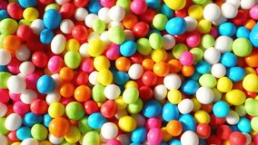 A macro video captures the sugar sprinkles in multicolor balls. Tiny, vibrant spheres cascade and bounce, reflecting light in a dazzling spectacle. Watch as they add a delightful touch to treats.
