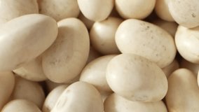 The macro video reveals dried white kidney beans up close, showcasing their pearl-like texture with tiny crevices and imperfections, a testament to their natural growth and drying. Food concept
