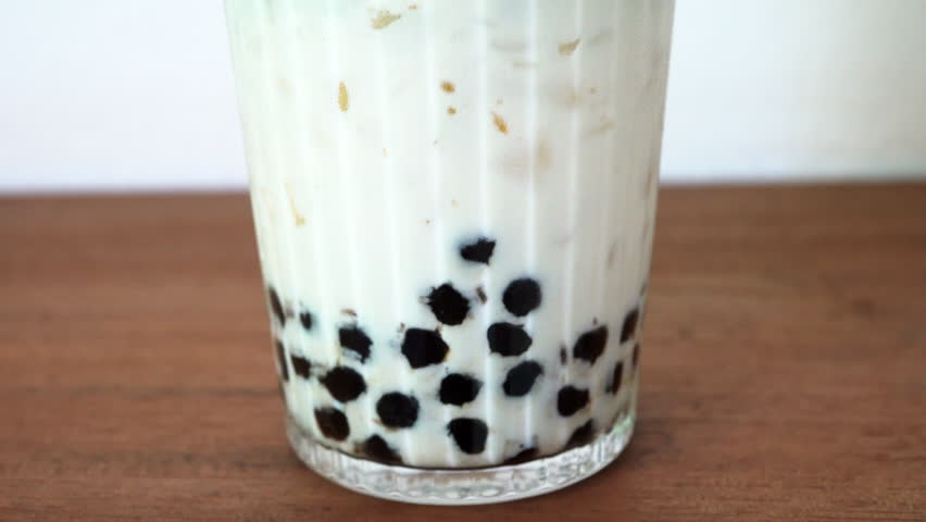 Bubble milk green tea in a clear glass on a wooden table