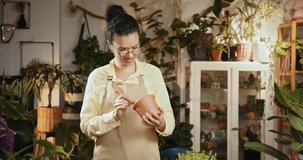 Small business entrepreneur and plant caring concept. A black woman transplants a houseplant, a flower in a ceramic pot