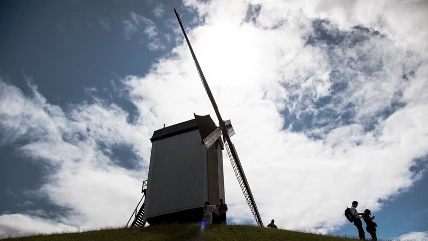 Bonne Chiere windmill Bruges Brugge Belgium Flanders historic landmark wooden mill architecture travel tourism heritage european scenic view sky clouds sun silhouette hill grass ancient flour grinding old