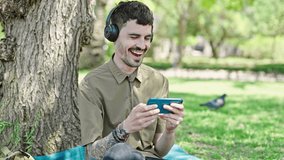 Young hispanic man smiling confident watching video on smartphone at park