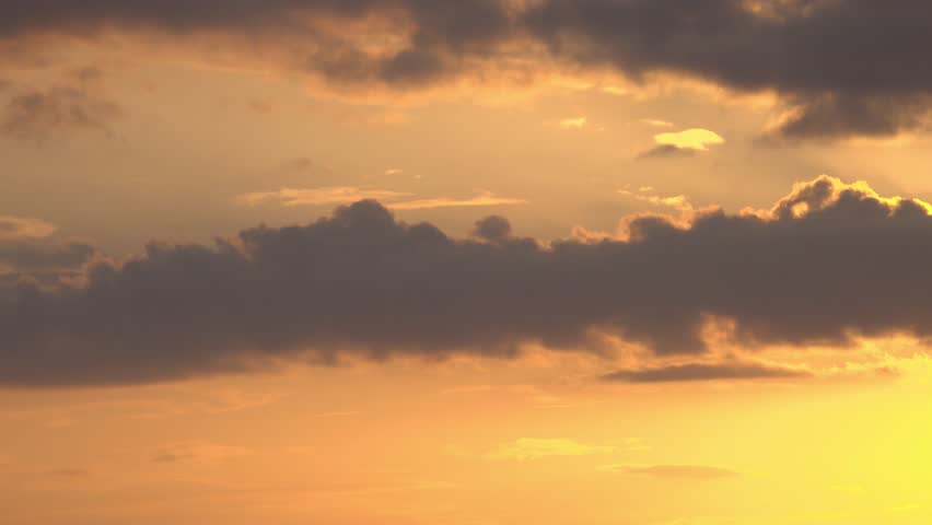 Long strip of dark clouds in the orange sky. Summer evening.