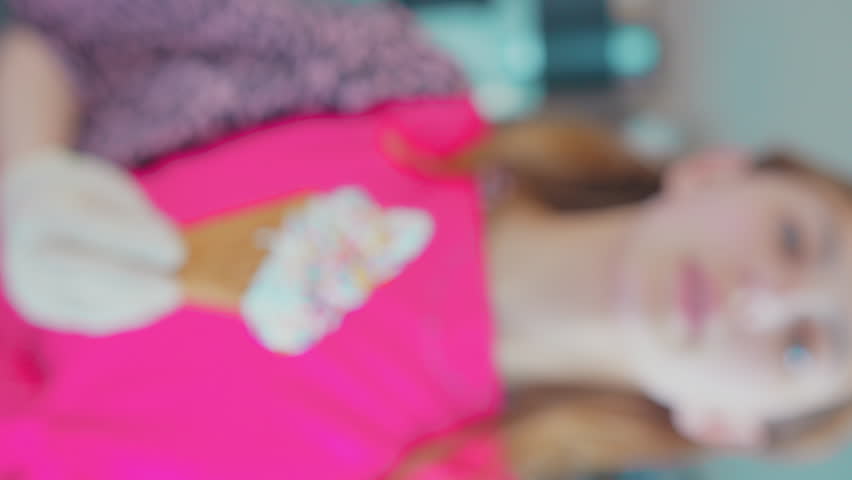 A young woman holds out in her hand ready-made ice cream in a waffle glass sprinkled with multi-colored sugar sprinkles
