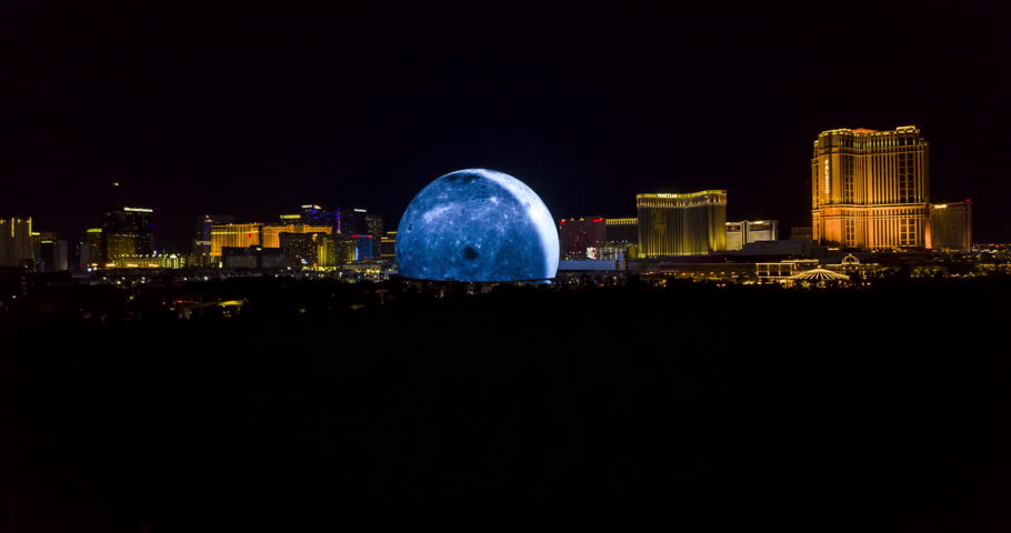 Las Vegas, Nevada USA - August 5th 2023:  The brand new MSG Sphere entertainment venue mimics the moon as it illuminates the surrounding Las Vegas city skyline in this  aerial drone time-lapse.