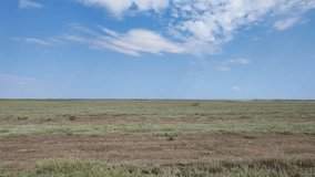 Steppe landscape, summer nature, desert area. Village in the distance. Blue sky with clouds. Simple video.