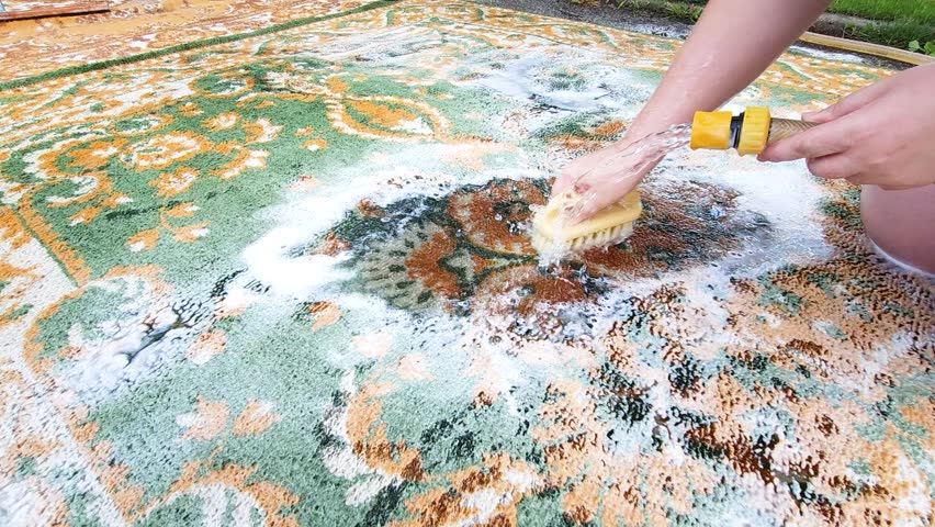 Washing carpets with a brush with detergents in the yard