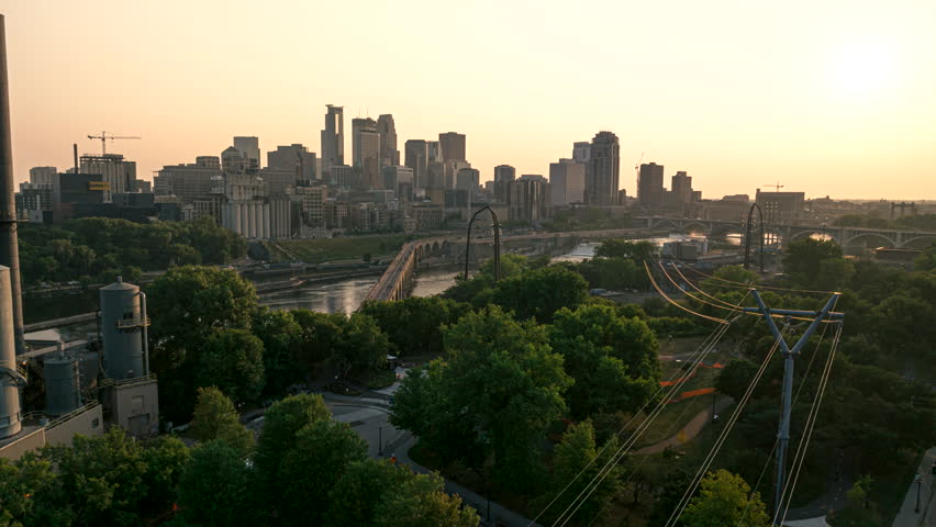 Sunset aerial hyperlapse over Hennepin Island along Stone Arch Bridge, wildfire haze over City of Minneapolis skyline, Minnesota, USA