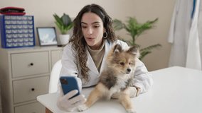 Young hispanic woman with dog veterinarian smiling confident having video call at clinic
