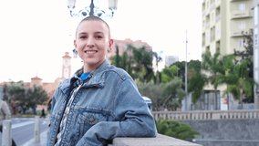 4k video of young woman with shaved hair walking through the city and smiling. Concept: lifestyle, city life, urban style	