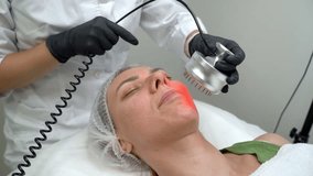 process of using infra red lights tool. Professional treatment cosmetology. Relaxed patient young woman  with closed eyes during procedure. Modern cosmetology anti aging skin care video footage