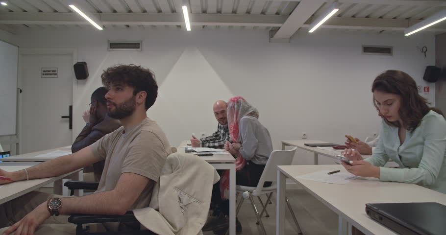Diverse colleagues making a test of knowledge in the office education center, one colleague sitting in wheelchair, trucking motion Royalty-Free Stock Footage #1107399913