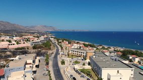 Over the road and green Forest in Rhodes with seaside in the background in Greece during the summer filmed with the drone in 4K