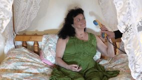 Hand is giving landline phone receiver or handset to long haired happy woman in green retro style dress on canopy or four-poster bed. She is smiling to somebody behind the curtain and while talking. - Powered by Shutterstock - Get 15% off with code: PIKWIZARD15