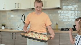 vertical video, happy family, little cute girl 6 years old having fun cooking pizza at home with mom, home food concept. High quality 4k footage