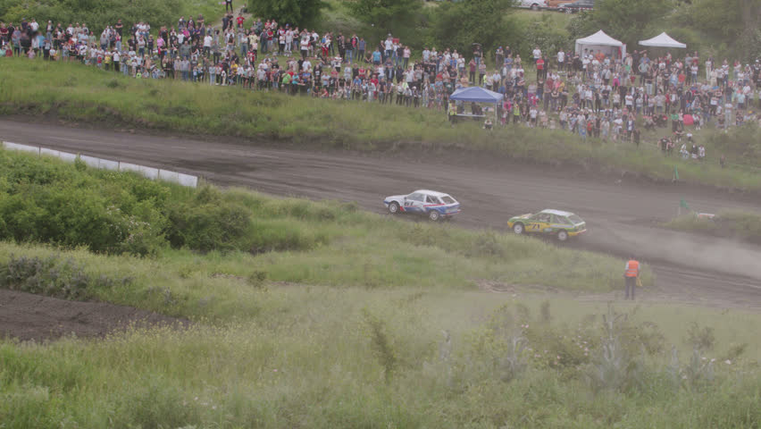 Aerial image of a sports car racing competition. Several cars start from the star line on a bumpy and dangerous route on the hills. Many supporters, fans and spectators