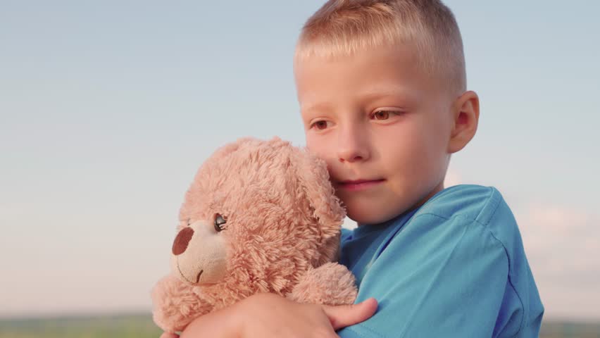Child plays with Teddy bear. Kid plays with toy, Plush toy in hands of boy, child in summer park. Cute chilld baby boy hugs his favorite soft teddy bear on playground. Portrait of child with bear toy Royalty-Free Stock Footage #1107407305