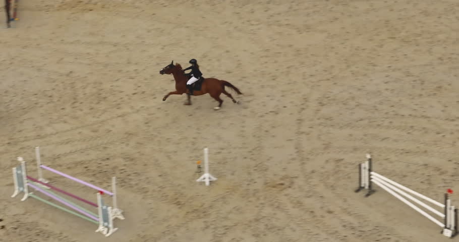 Jockey on a horse running around a dirt track at sunset. Equestrian sport, competition outdoors. Sprinting horse