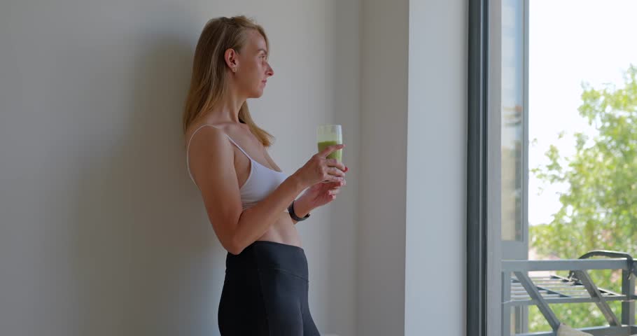 Attractive fit woman in sport uniform drinking smoothies