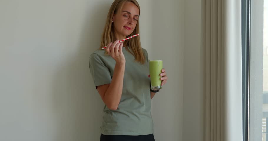 Attractive fit woman in sport uniform drinking smoothies