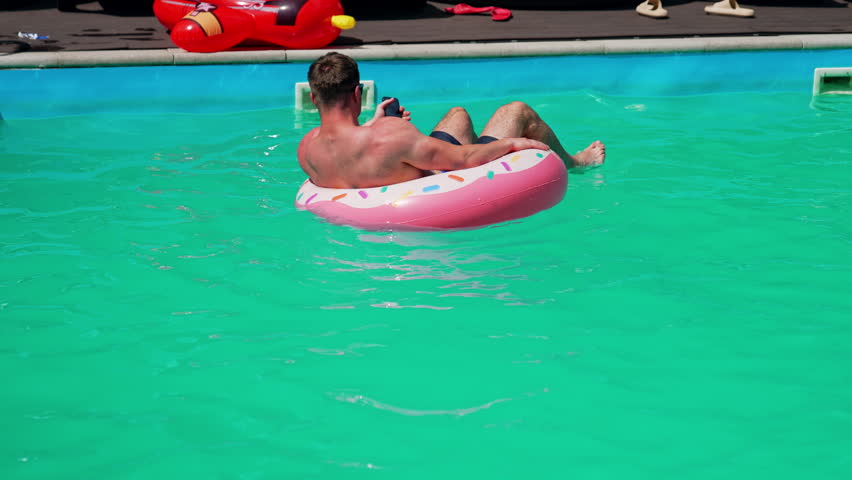 Attractive vacation lifestyle near pool. Man in pool swimming.