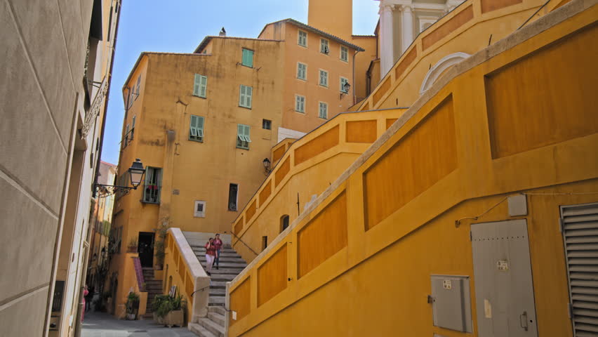 Tourists visit Basilique Saint-Michel Archange de Menton. People taking pictures of the colored buildings in Menton, French Riviera.
